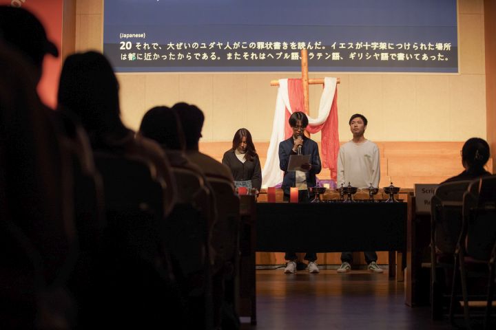 A person standing at a podium in front of a group of peopleDescription automatically generated with medium confidence